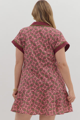 Woman wearing a pink patterned dress with maroon trim on a white background