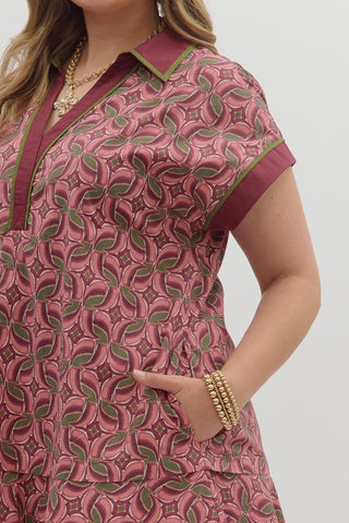 Woman wearing a pink and green patterned dress with a plain background