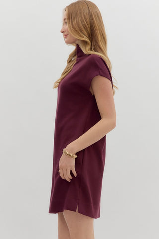 Woman wearing a burgundy dress on a light gray background