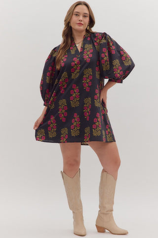 Woman wearing a dark floral dress with beige knee-high boots on a white background