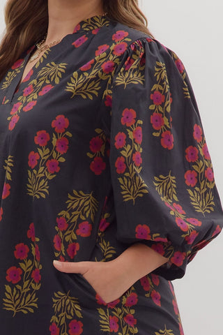 Woman wearing a dark floral dress with pink and yellow flowers on a white background
