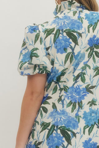 Floral patterned shirt with blue flowers and green leaves on a plain background