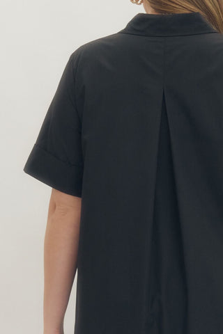 Black shirt worn by a person on a plain background