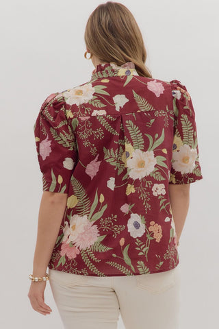 Woman wearing a floral blouse with puff sleeves on a white background