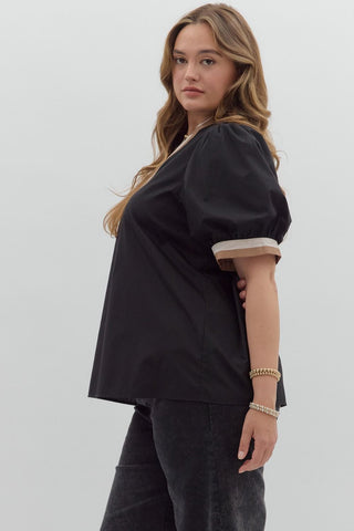 Woman wearing a black blouse with white trim on a plain background