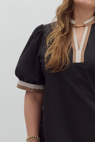 Black top with white trim worn by a person on a plain background