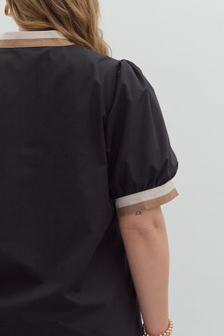 Person wearing a black outfit with white trim on a plain background