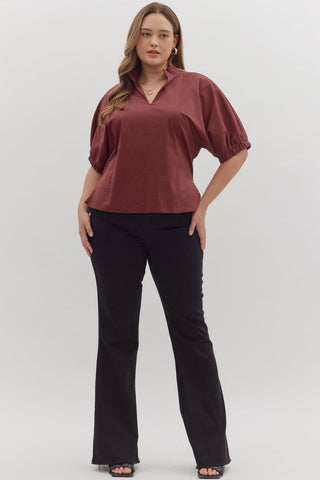 Woman wearing a burgundy top and black pants on a white background