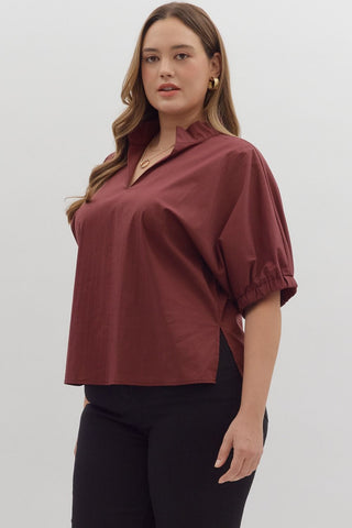 Woman wearing a maroon top and black pants on a white background