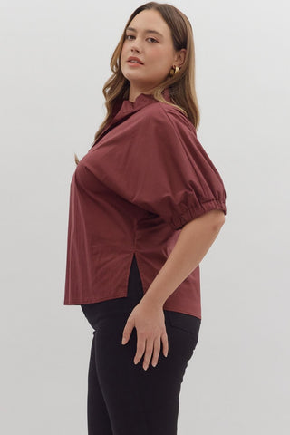 Woman wearing a burgundy blouse and black pants on a white background