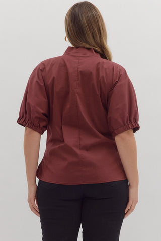 Person wearing a maroon shirt and black pants on a white background