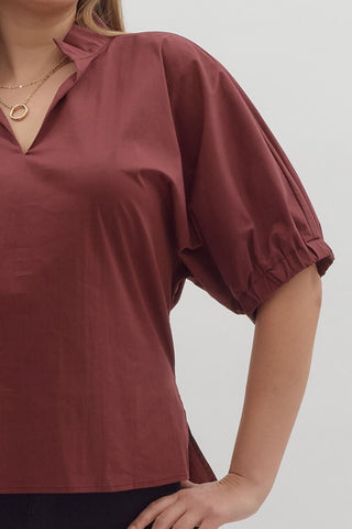 Maroon blouse with puff sleeves worn by a person on a plain background