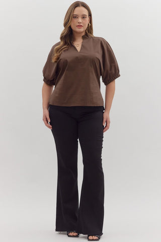 Woman wearing a brown blouse and black pants on a white background