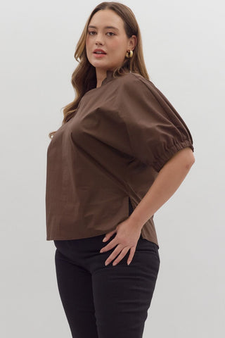 Woman wearing a brown blouse and black pants on a white background