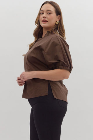 Woman wearing a brown blouse and black pants against a white background