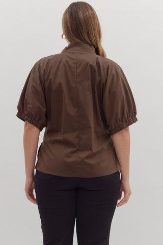 Person wearing a brown shirt with short sleeves on a white background