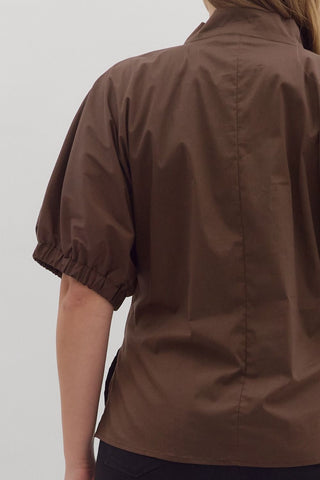 Brown short-sleeve shirt worn by a person on a plain background