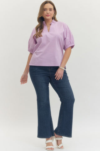 Woman wearing a light purple blouse and blue jeans on a white background