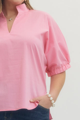 Person wearing a pink blouse with a plain background