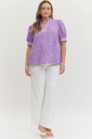 Woman wearing a purple blouse and white pants on a white background