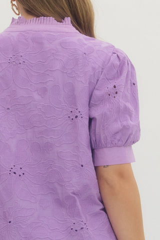 Purple blouse with puff sleeves worn by a person on a white background