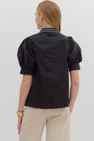 Person wearing a black blouse with puff sleeves on a white background
