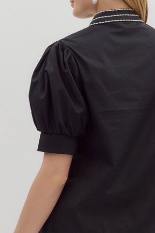 Black blouse with puffed sleeves on a plain background
