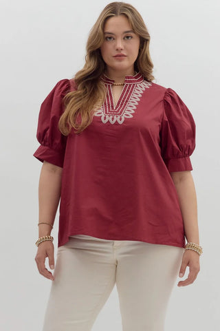 Woman wearing a red blouse with white embroidery on a white background