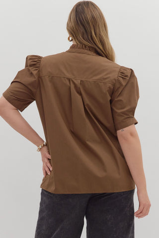 Woman wearing a brown blouse with ruffled sleeves on a white background