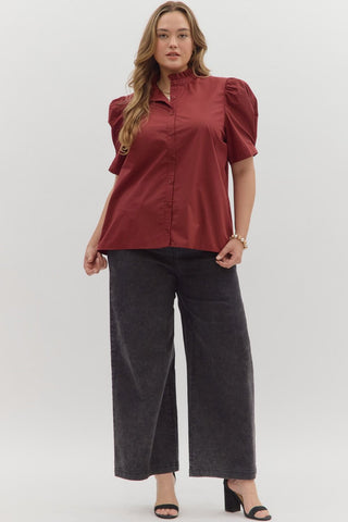 Woman wearing a red blouse with puff sleeves and dark pants on a white background