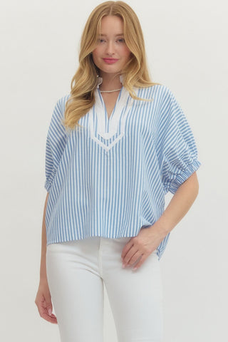 Woman wearing a blue and white striped blouse with a plain background