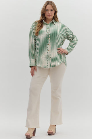 Woman wearing a green and white striped shirt and beige pants on a white background