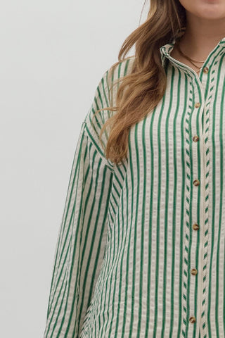 Green and white striped shirt worn by a person on a plain background