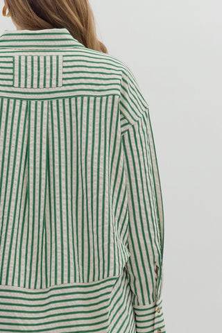 Green and white striped shirt worn by a person on a plain background