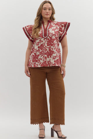Woman wearing a red floral blouse and brown pants on a white background