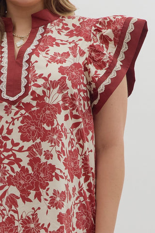Red floral dress with white lace trim on a plain background