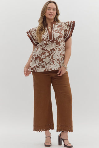 Woman wearing a floral top and brown pants on a white background