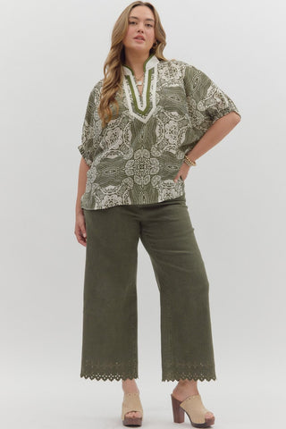 Woman wearing a green patterned blouse and green pants on a white background
