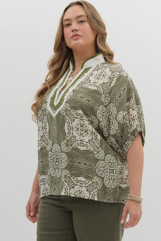 Woman wearing a patterned top and green pants on a white background