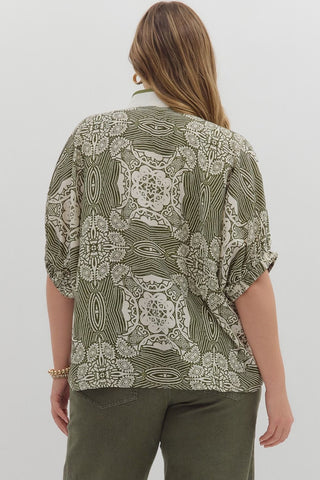 Woman wearing a patterned shirt and green pants on a white background
