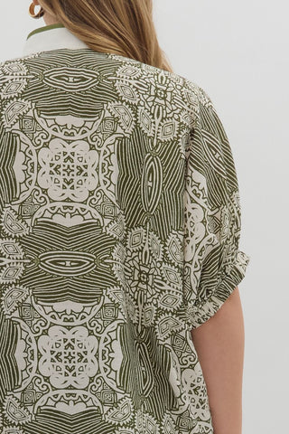 Person wearing a patterned shirt with green and white design on a plain background