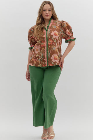 Woman wearing a floral blouse and green pants on a white background