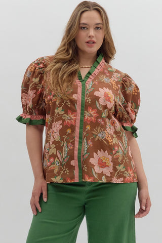 Woman wearing a floral blouse with puff sleeves and green pants on a white background