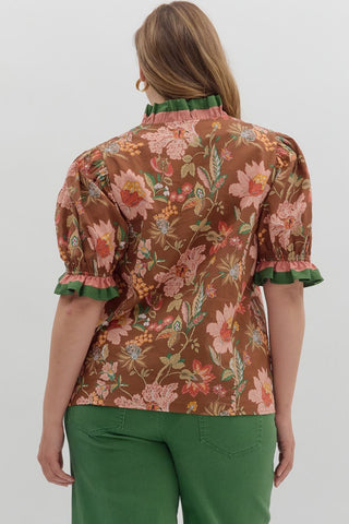 Woman wearing a brown floral blouse with green trim on a white background