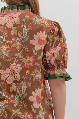 Floral patterned blouse with green trim on a plain background