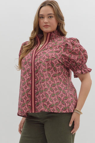 Woman wearing a pink patterned blouse with puff sleeves on a white background