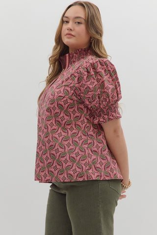 Woman wearing a pink patterned blouse and green pants on a white background
