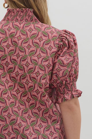 Close-up of a patterned blouse with ruffled sleeves on a plain background