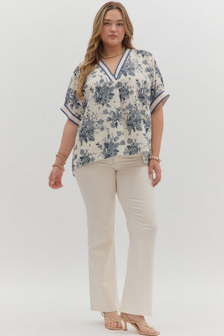 Woman wearing a floral blouse and beige pants on a white background