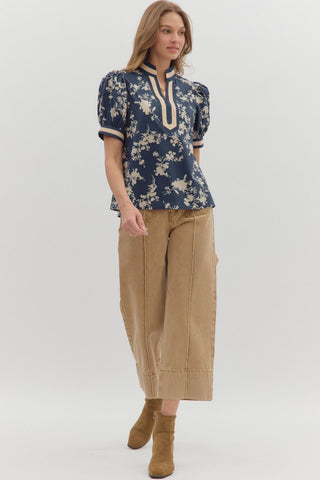 Woman wearing a blue floral blouse and beige pants on a white background